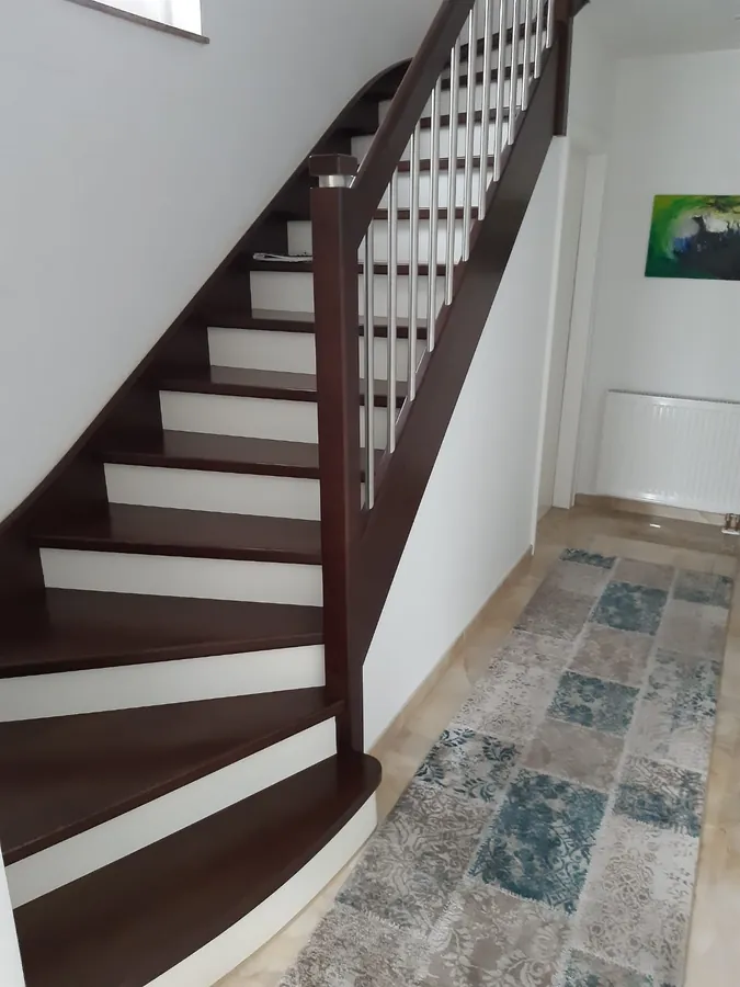 Gebogene Holztreppe mit weißen Balustern – Referenzprojekt