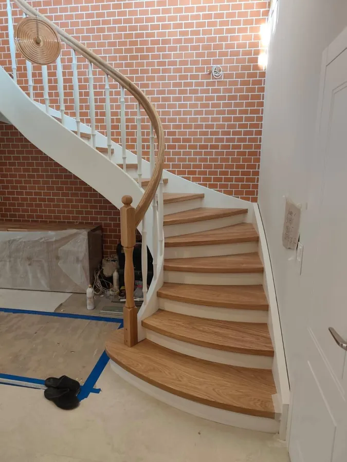 Gebogene Holztreppe mit weißen Balustern – Referenzprojekt